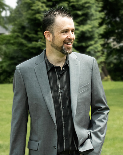 Chris, decently dressed, outside in a park